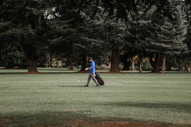 a man walking across a lush green field.